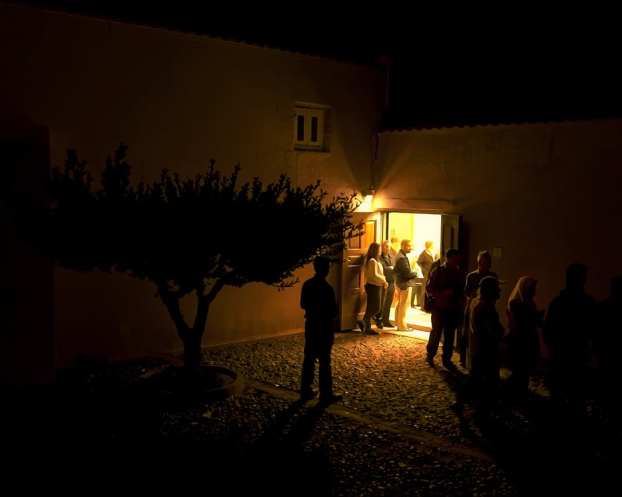 El patio de grava de ARENA de noche, con gente parada afuera de la puerta