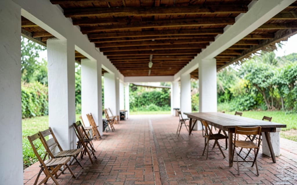 La galería techada con las columnas blancas y el piso de ladrillo, abierta al jardín