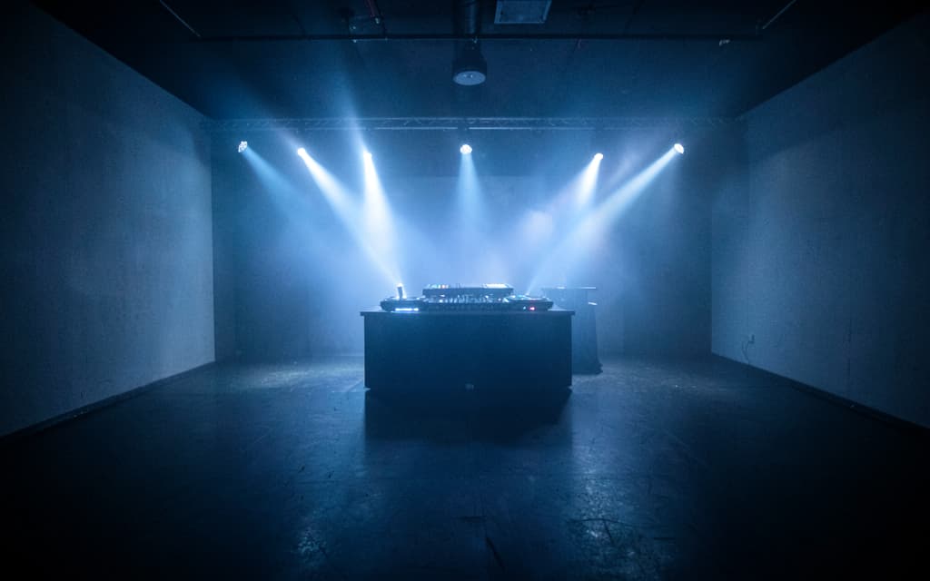 La sala principal en noche techno, vacía, con los haces de luz cruzando el humo