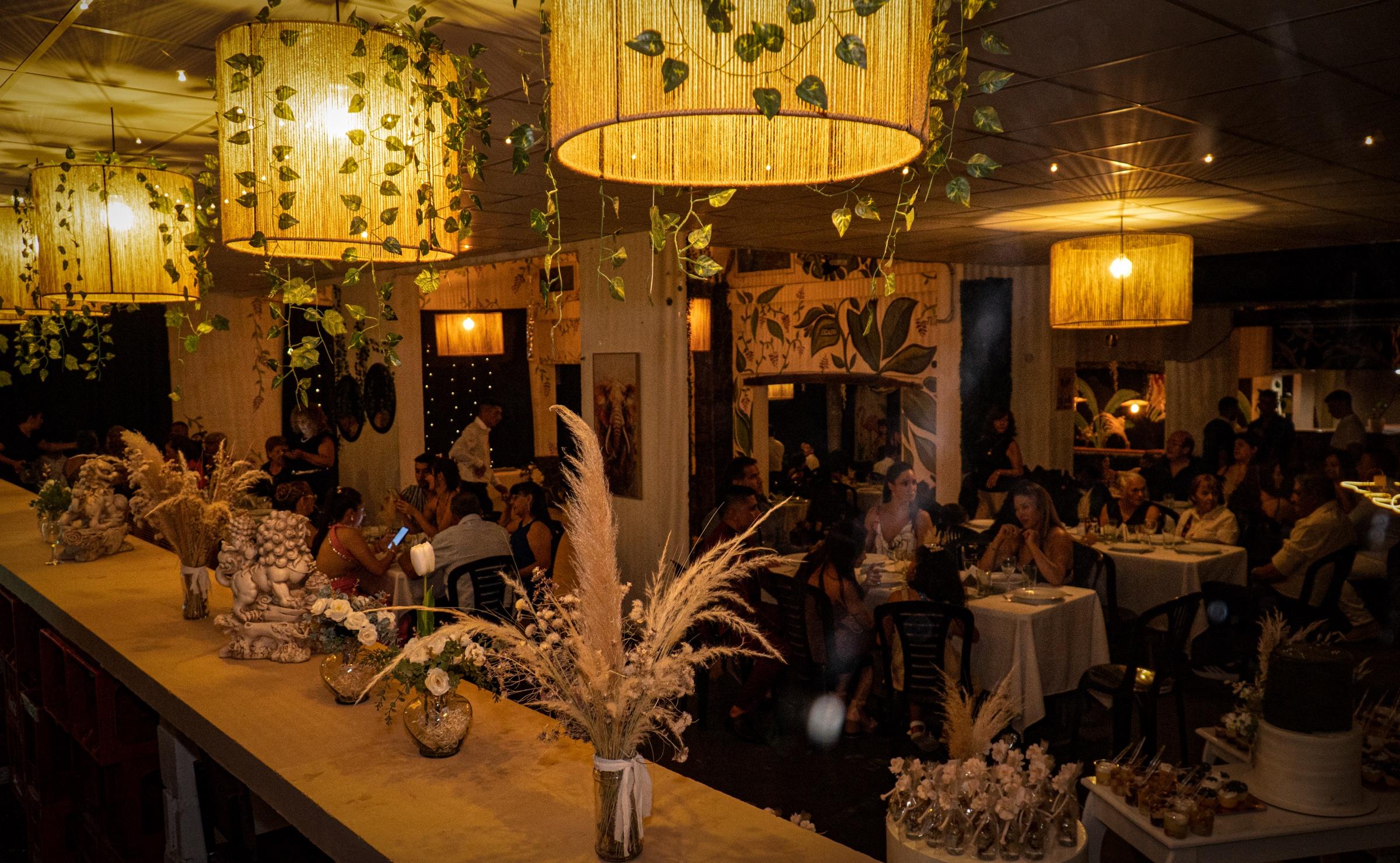 Salón interior en plena fiesta con lámparas de yute y murales tropicales