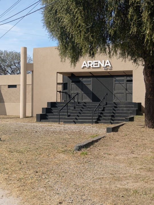 La entrada de ARENA de día, con la grava y el árbol