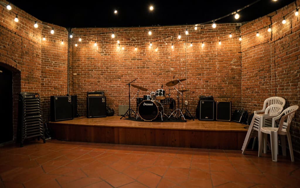 El patio armado para una banda en vivo, con el escenario bajo y los equipos puestos