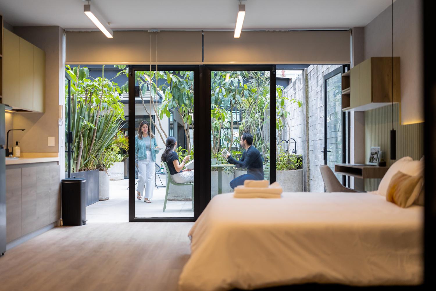 Bright bedroom opening onto a plant-filled patio
