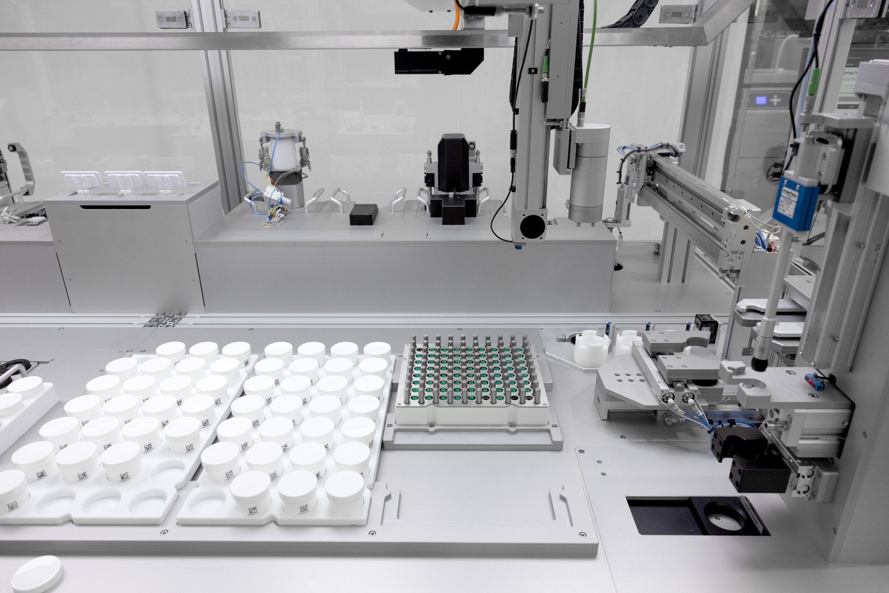 A formulation system with a rack of white pots and syringe tips