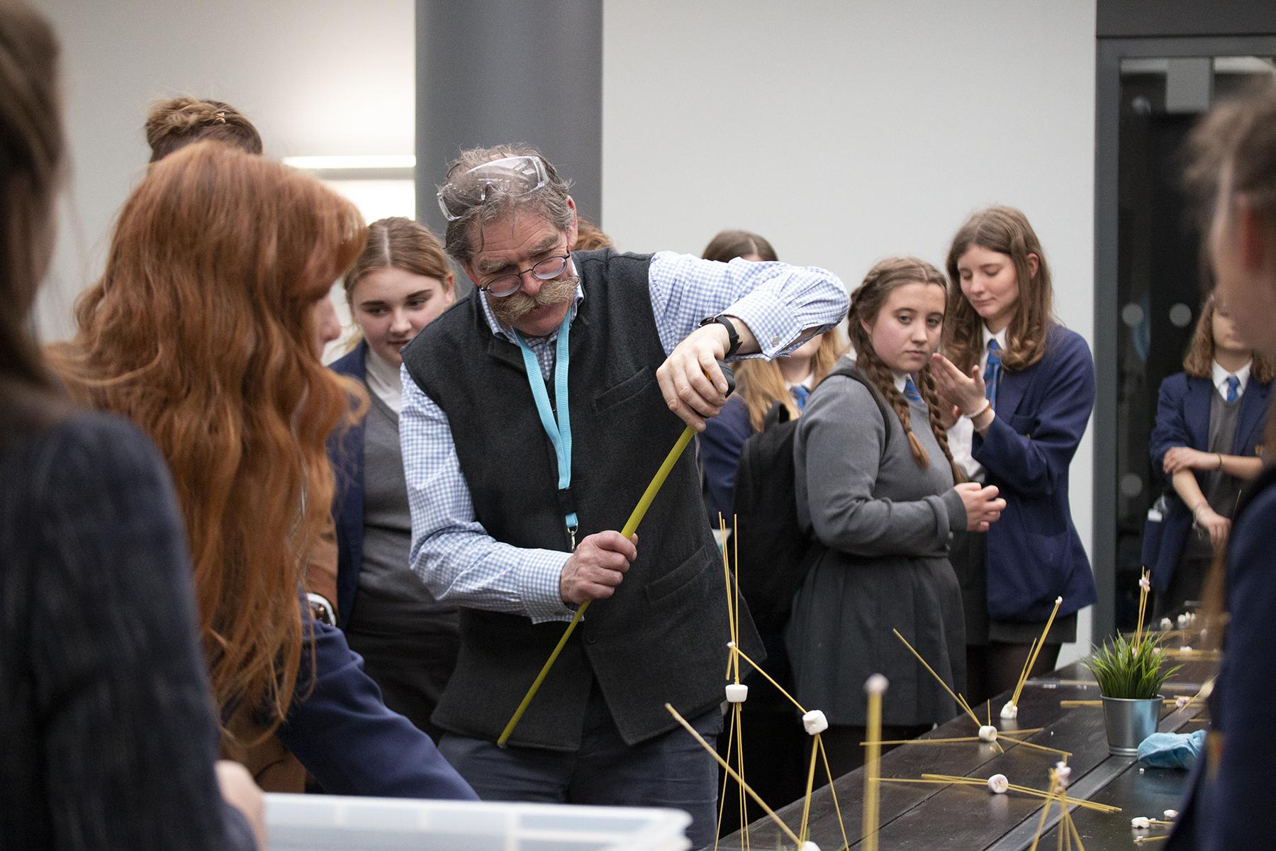 Female school students completing spaghetti and marshmallow tower challenge