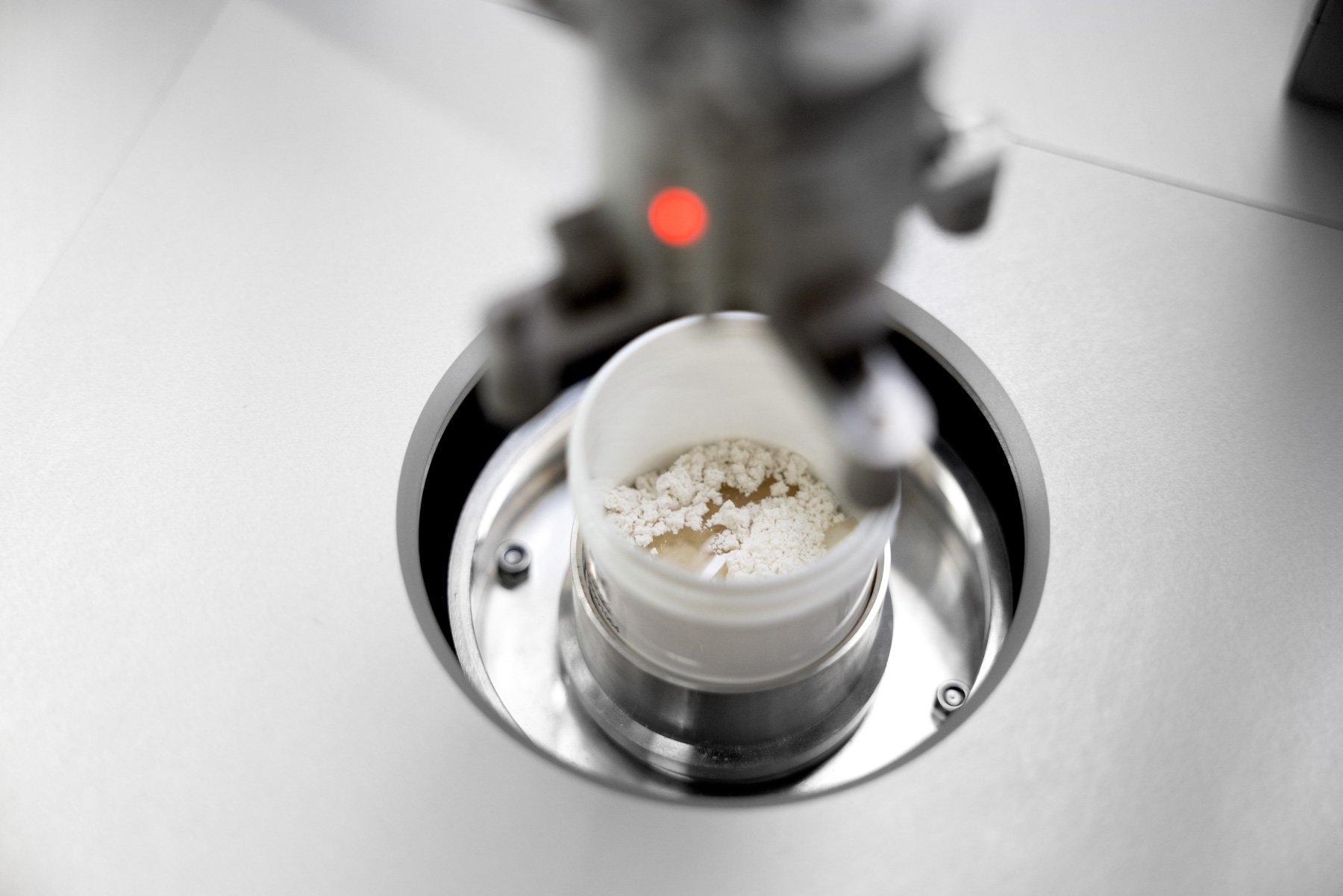A mixture of liquids and powders dispensed into a pot on an automated system