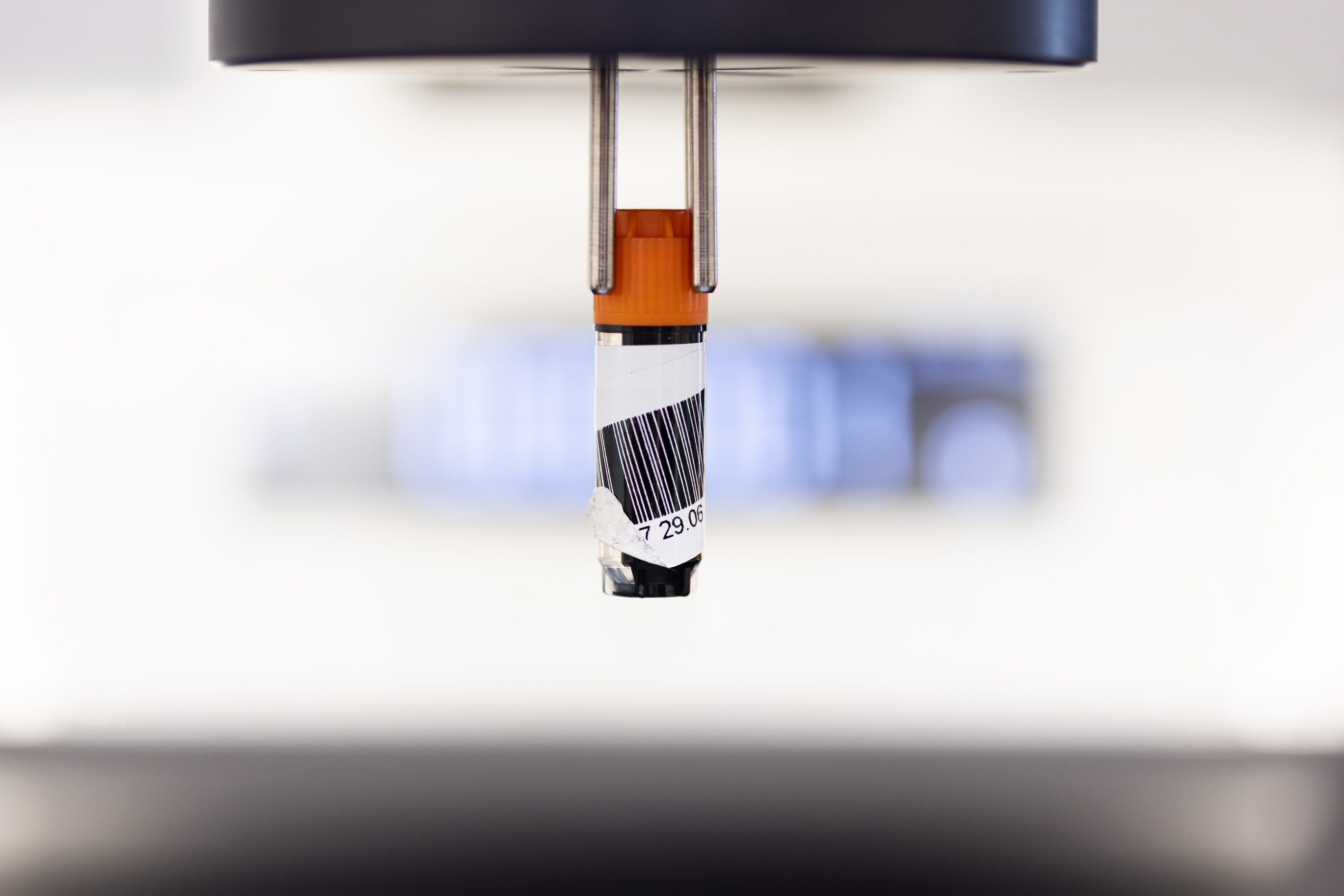 An Azenta vial in an automated gripper labelled poorly with a sticky label identifier