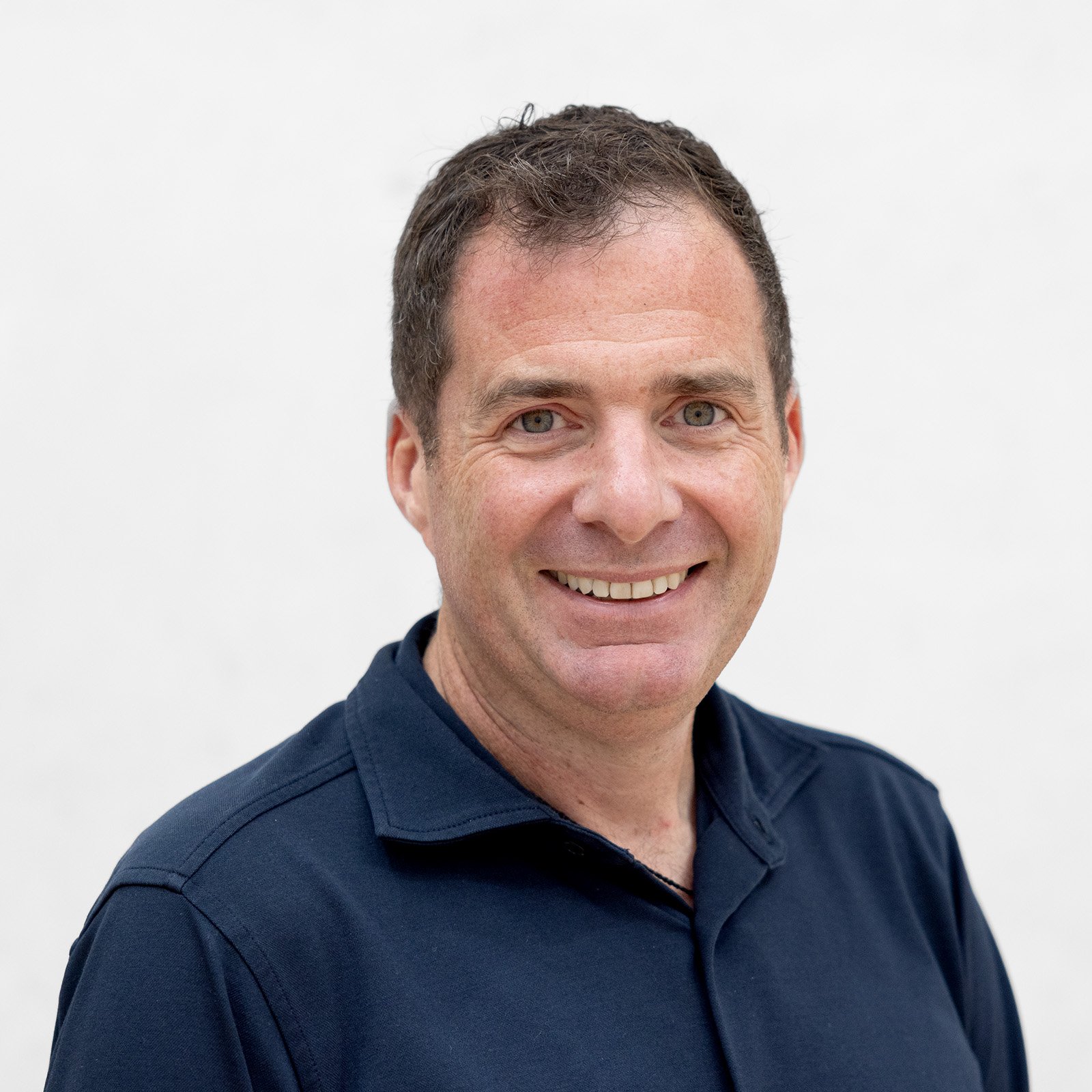 Headshot of a man in a blue shirt smiling 