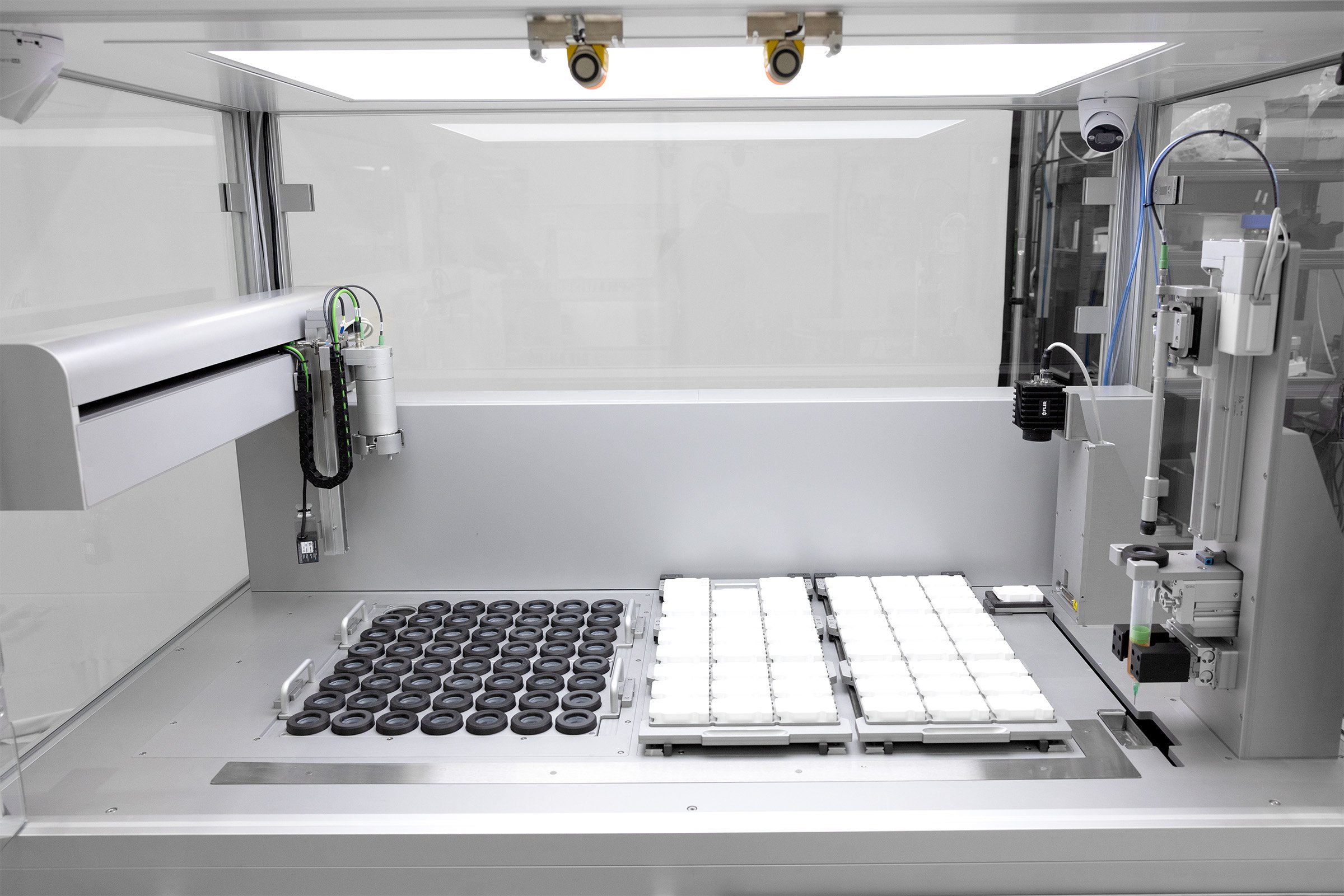 An automated polymerisation platform bed with racks of syringes and moulds