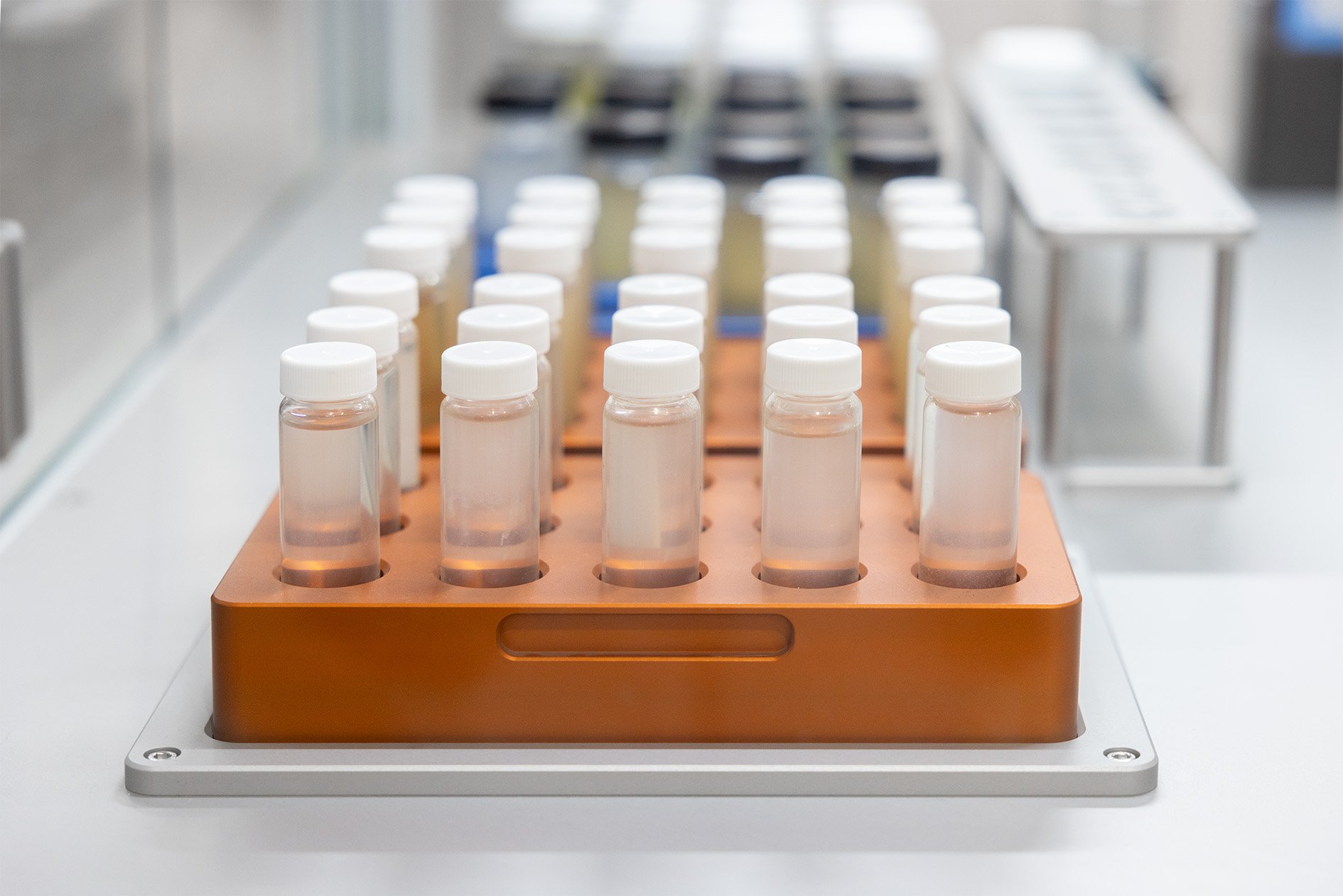 A rack of glass vials with white lids in a robotic system in a lab setting