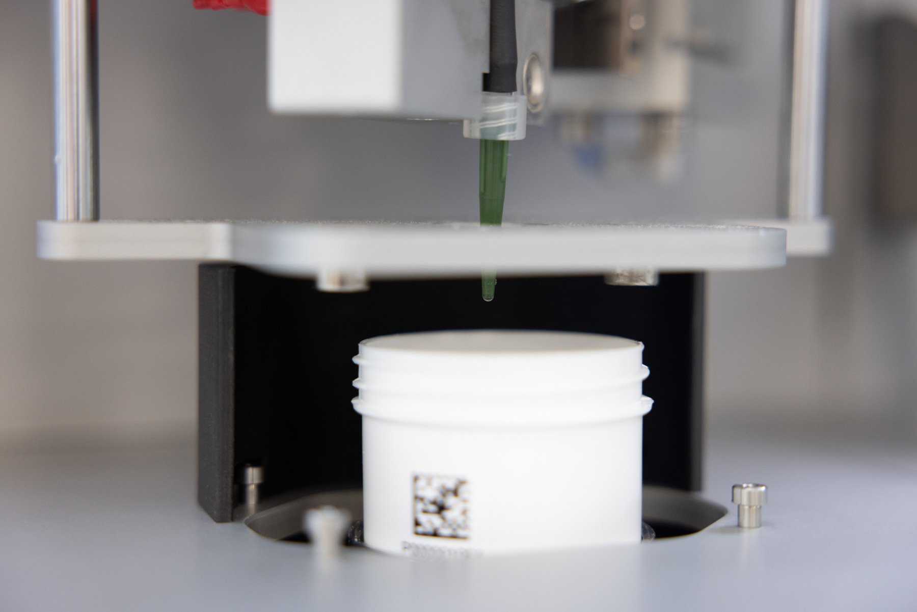 An automated robot dispensing liquid into a barcoded pot
