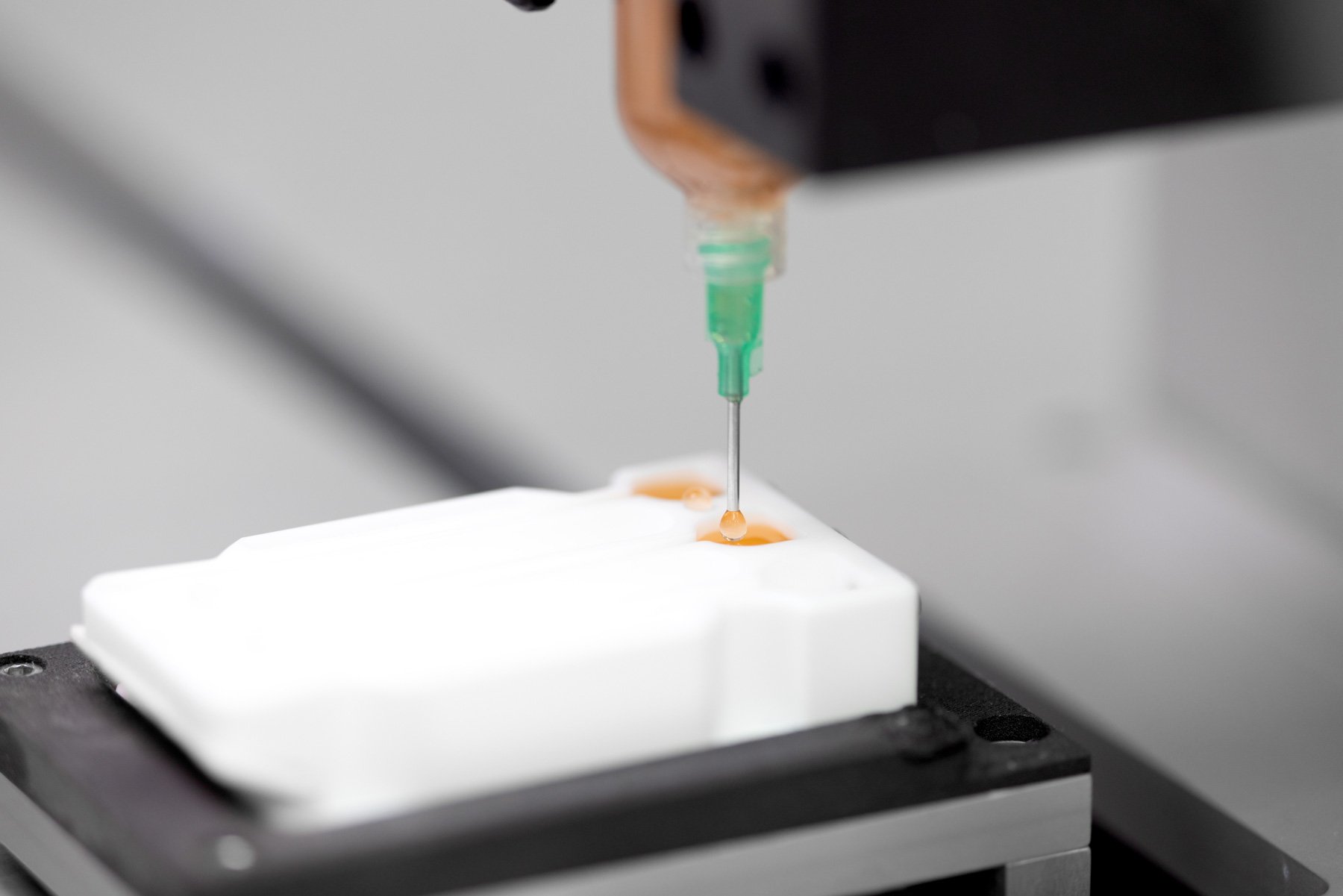 An orange liquid being dispensed from a syringe into a three channel mould