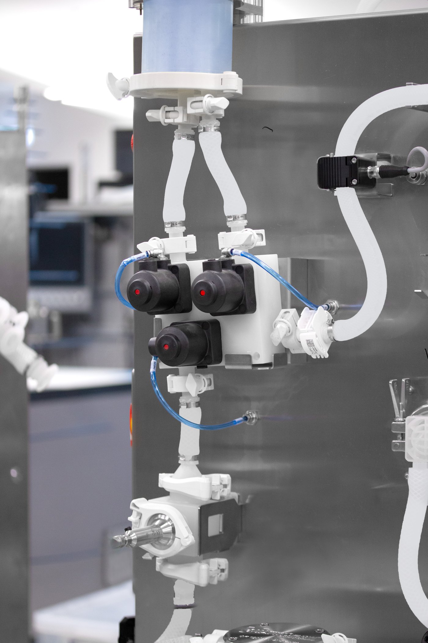 Steel metal Bioprocess skid close-up, showing white tubes, valves and pumps