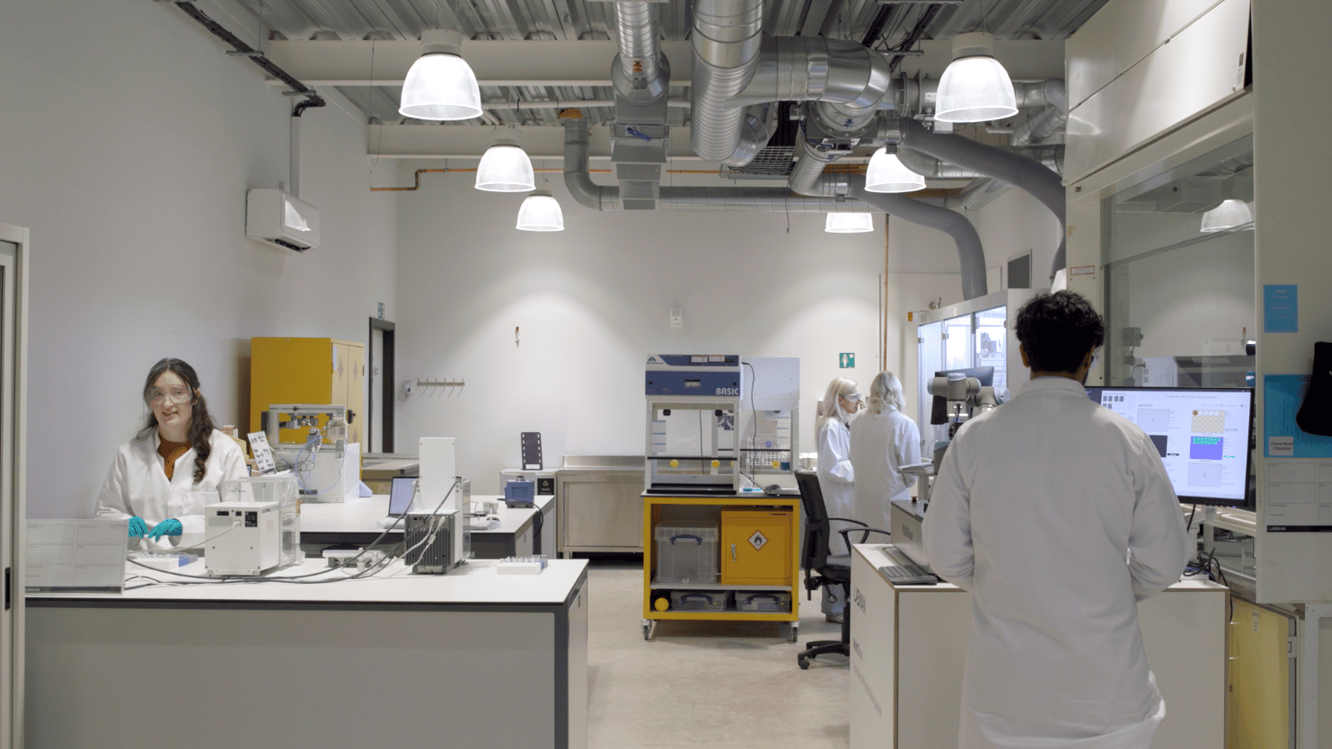 Four people wearing labcoats working in a laboratory with equipment