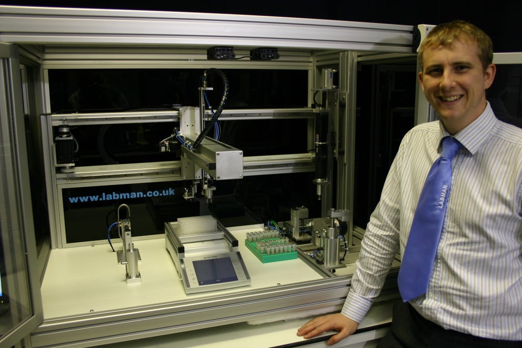 A labman custom robotic system with a man in a suit standing next to it 
