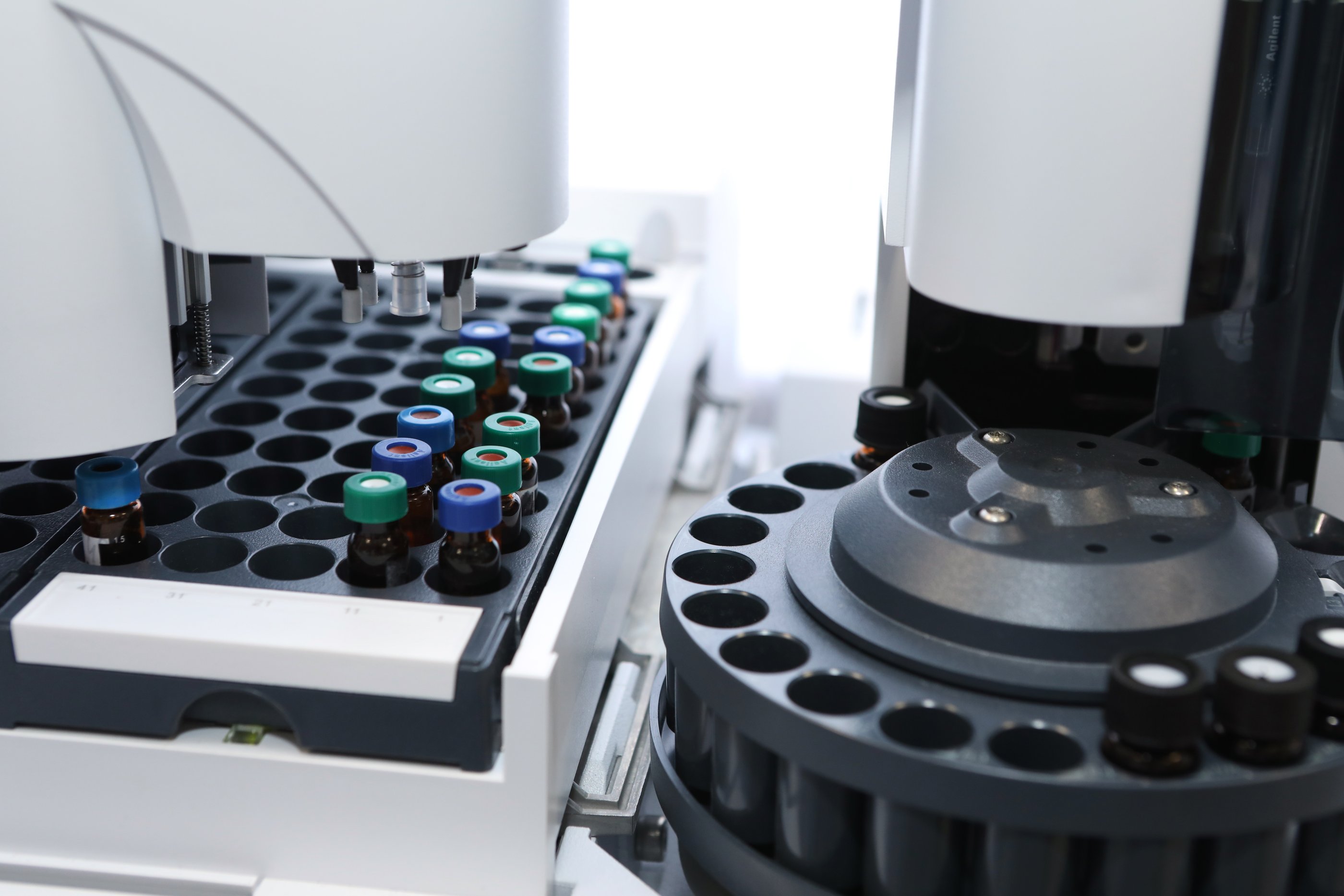 A HPLC high performance liquid chromatography device with several capped vials loaded into a grid with an autosampler