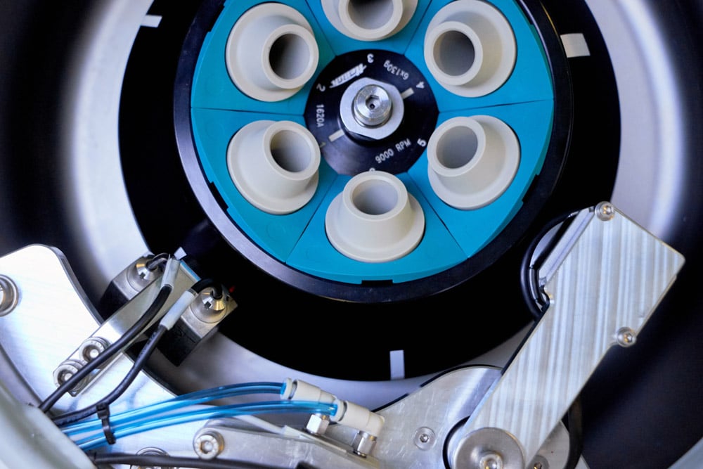 A black and blue circular robotic device with smaller white circles inside for liquid extraction