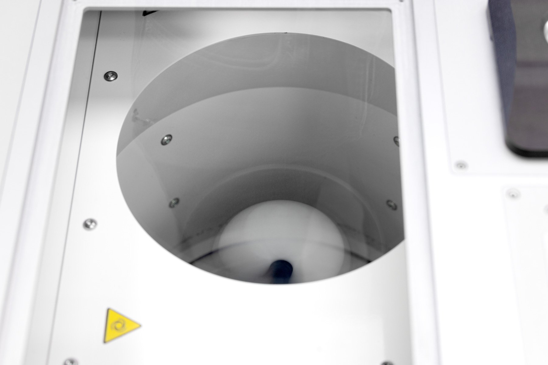 A dual asymmetric centrifuge (DAC) spinning with a white pot