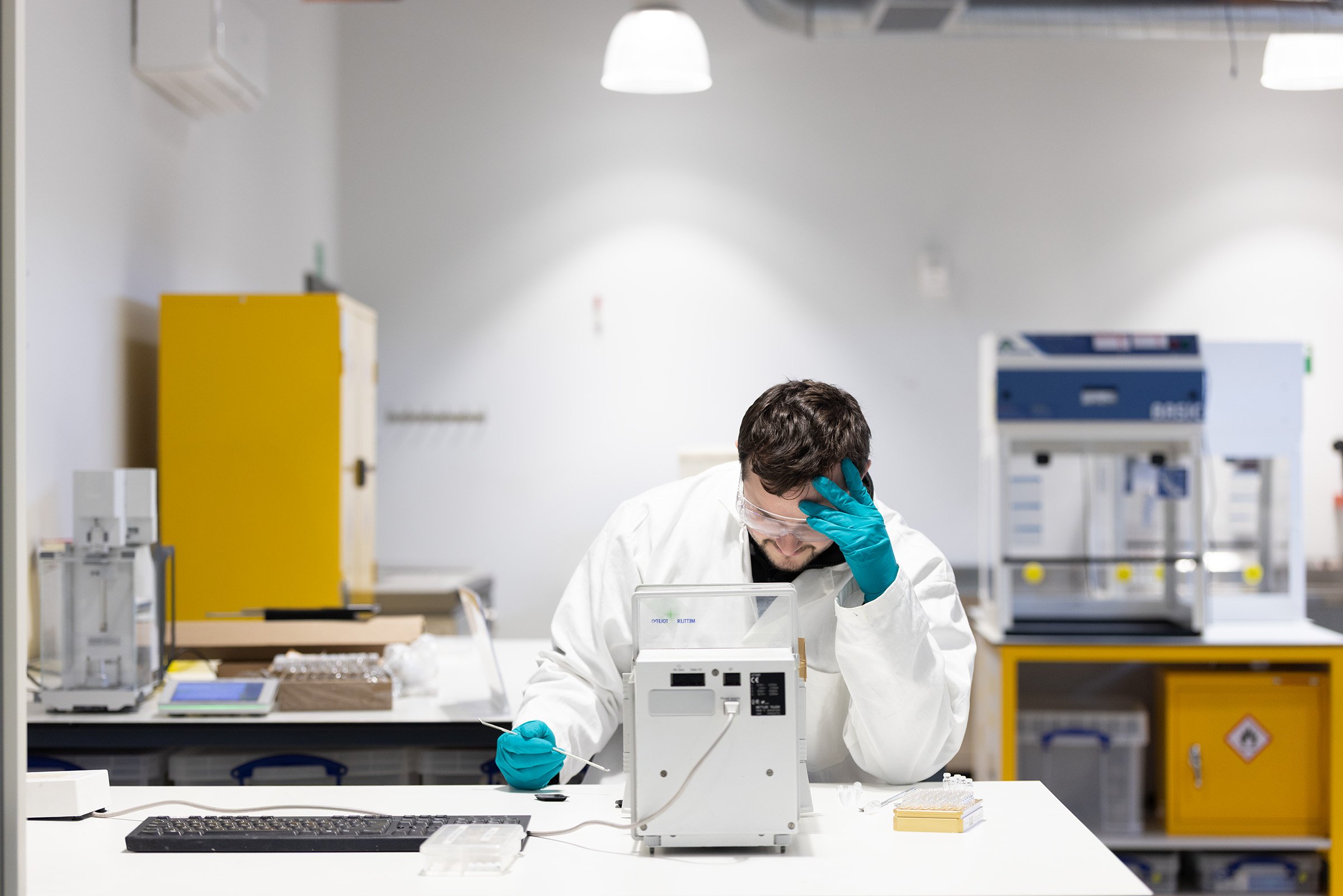 Man in a laboratory looking tired working at a benchtop