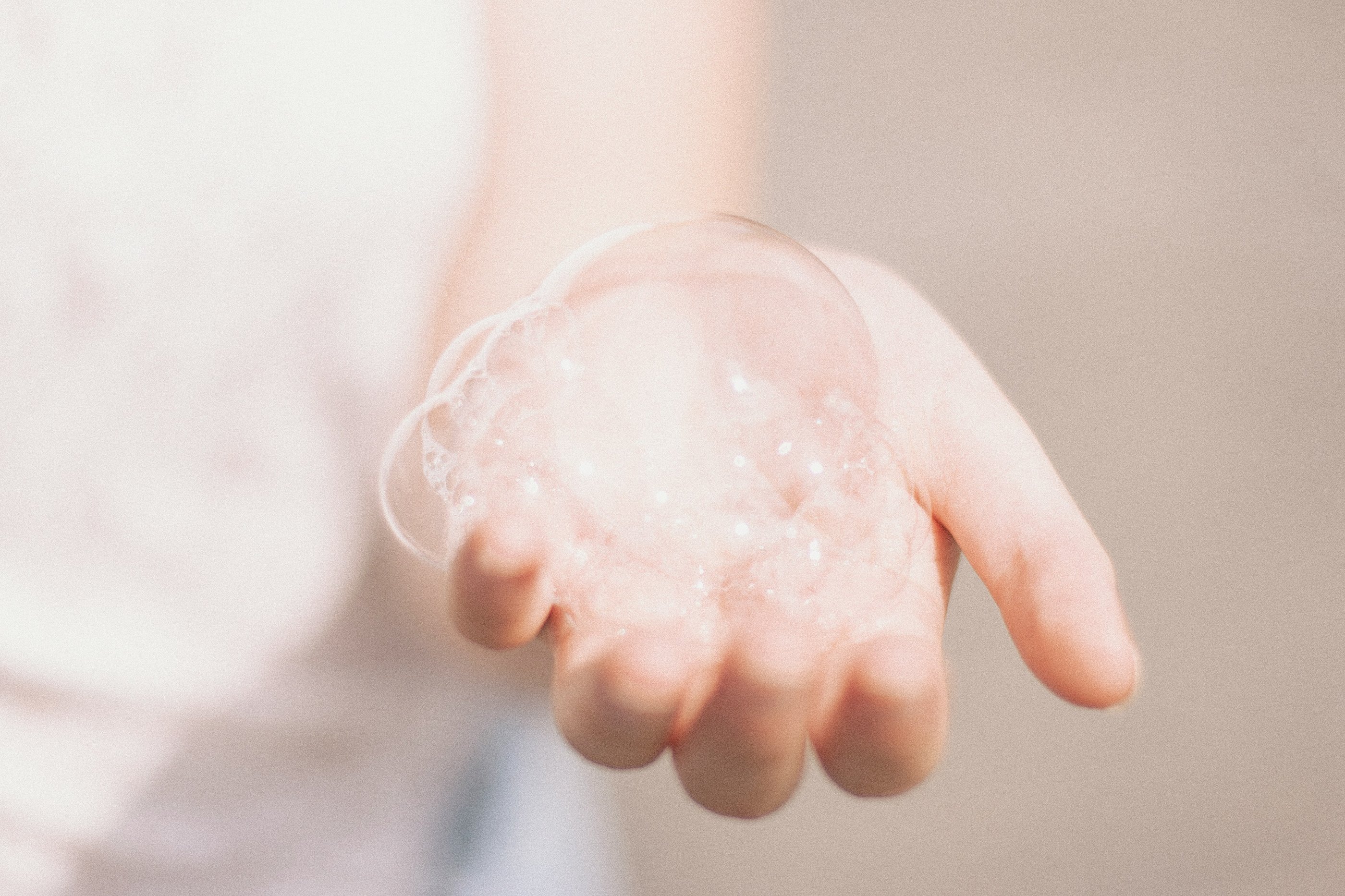 Person holding out their hand, which is holding some bubbles.