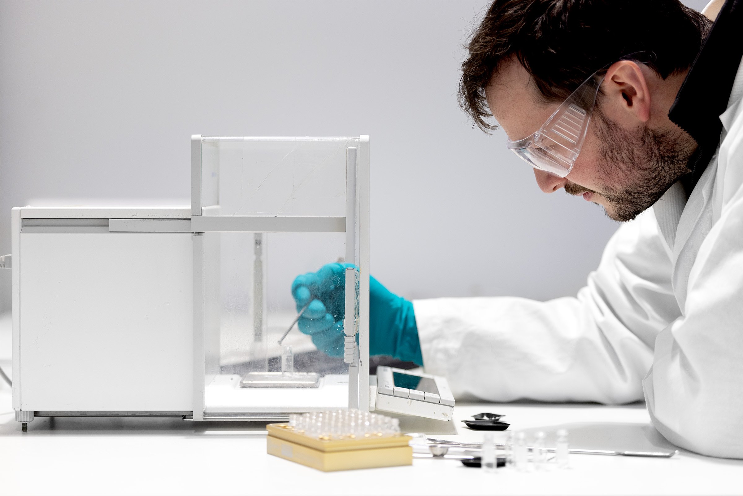 Man in a lab leaning over a balance weighing powders