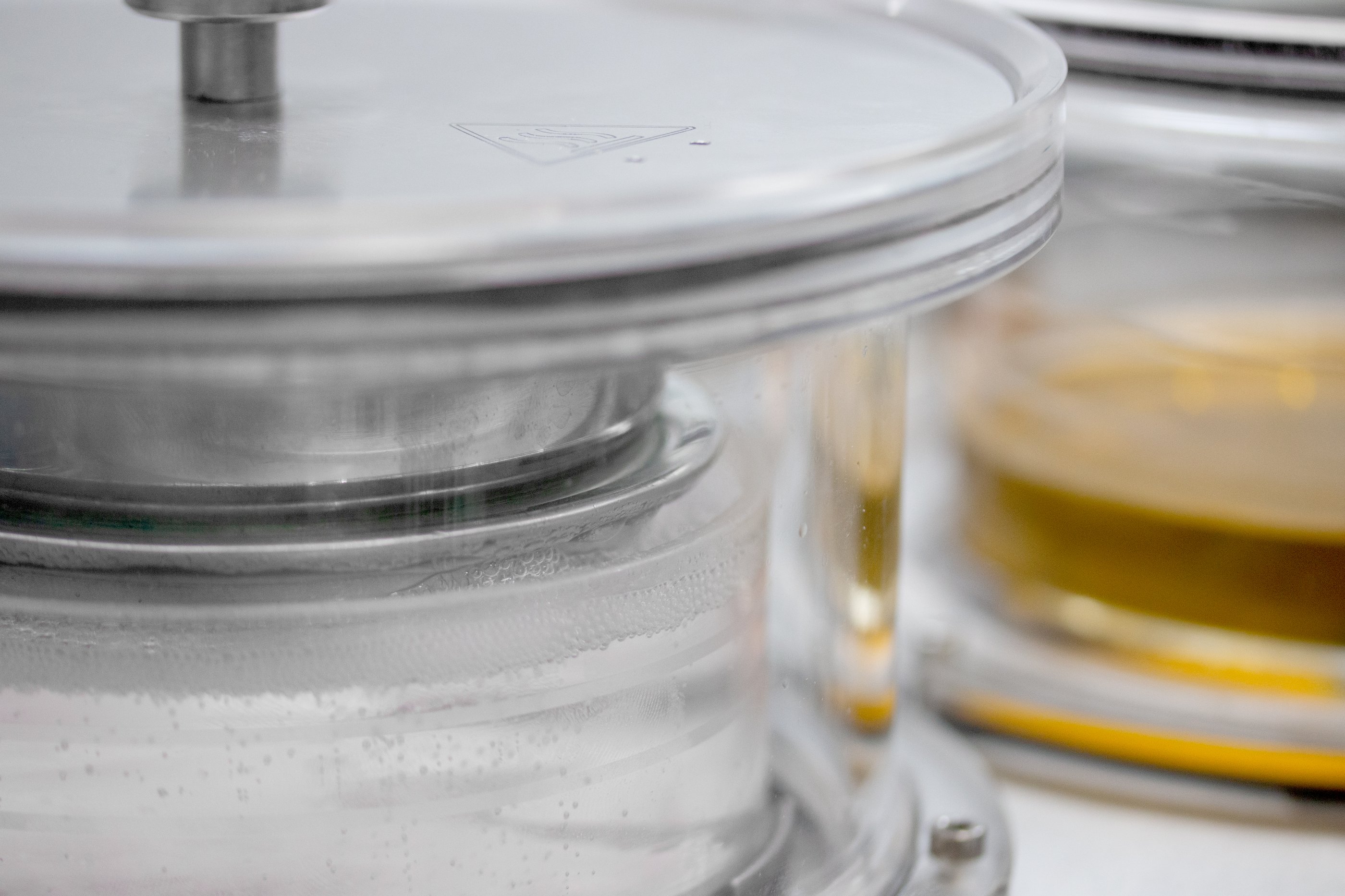 Dipping vessel containing a clear pot filled with a liquid solution. The steel basket containing porous pellets is submerged in the liquid