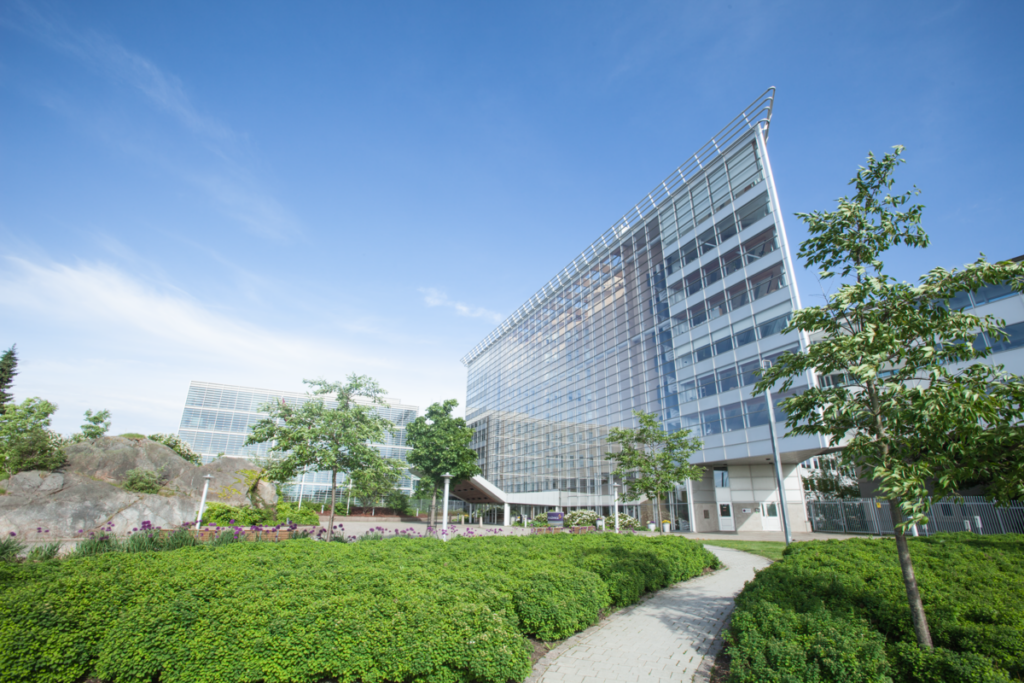 Tall pointy glass building with greeney in the foreground