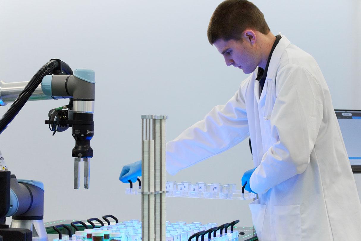 Man wearing a lab coat loading vials into Collaborative formulator