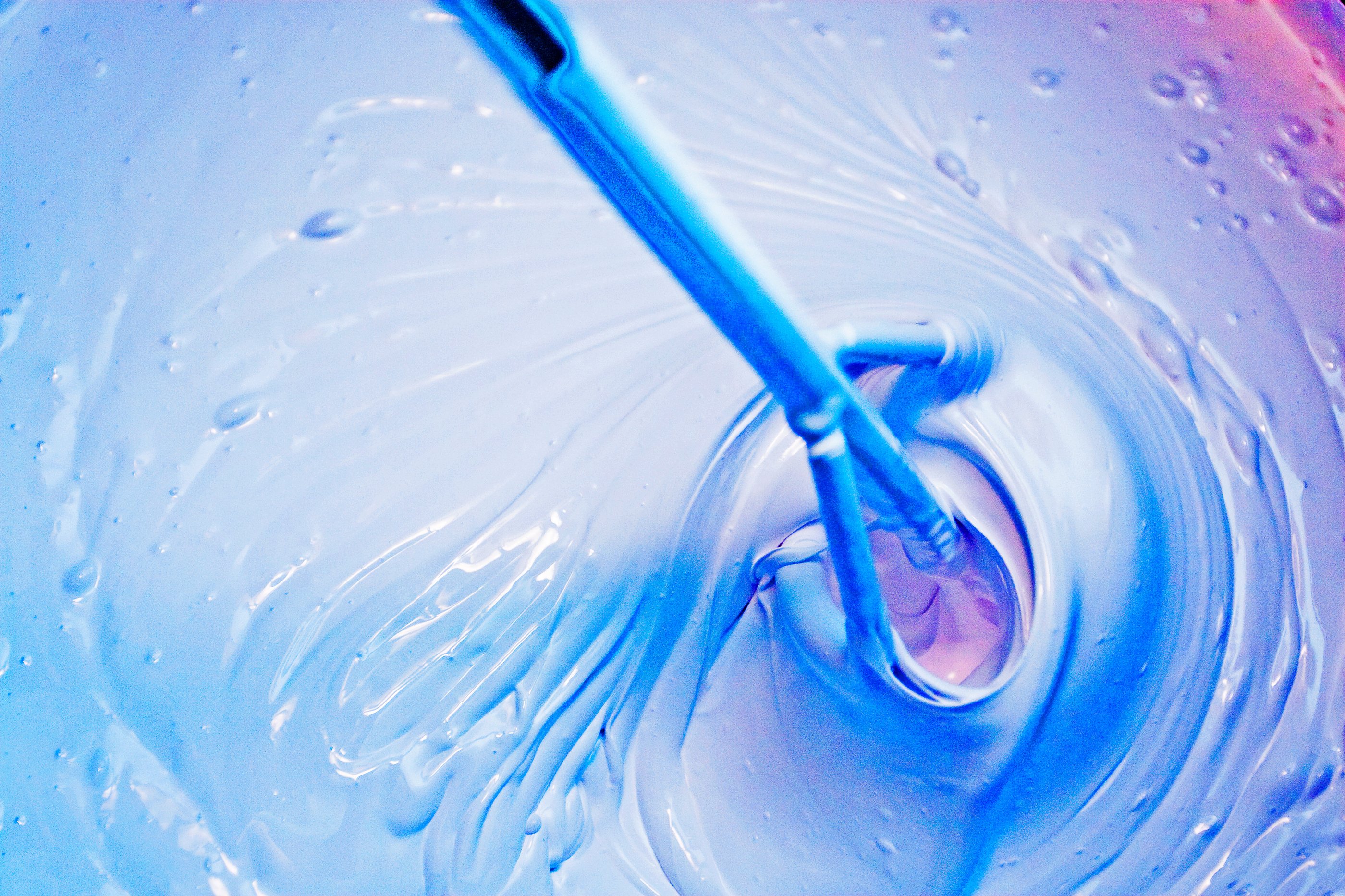 Paint mixer is being used in a large amount of blue paint to mix pingments in