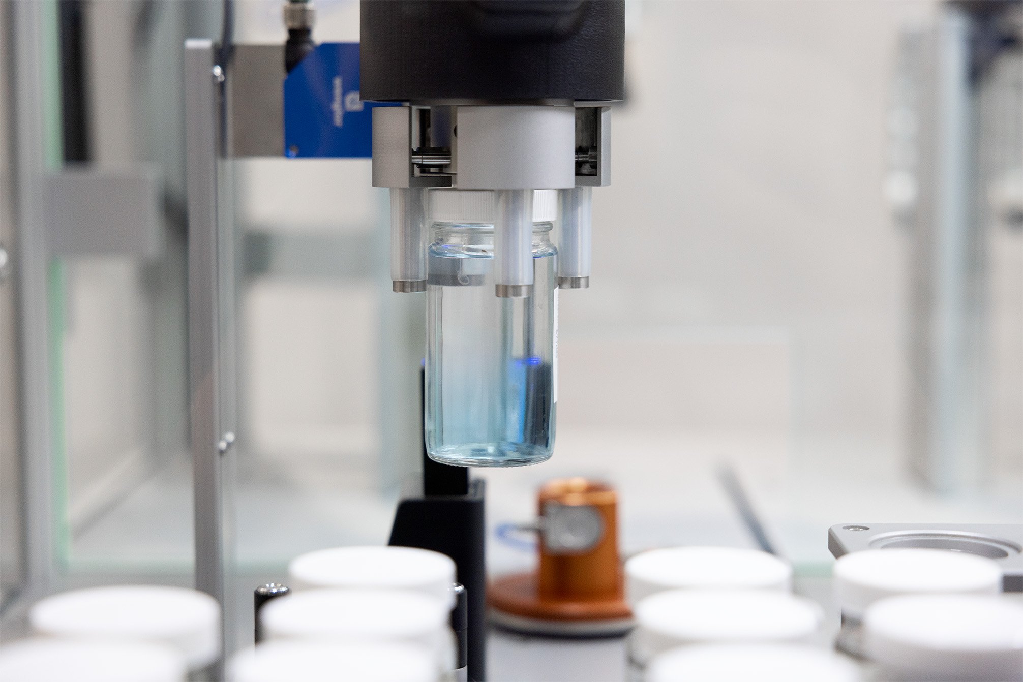 A jar of liquid in a robotic gripper in a lab environment
