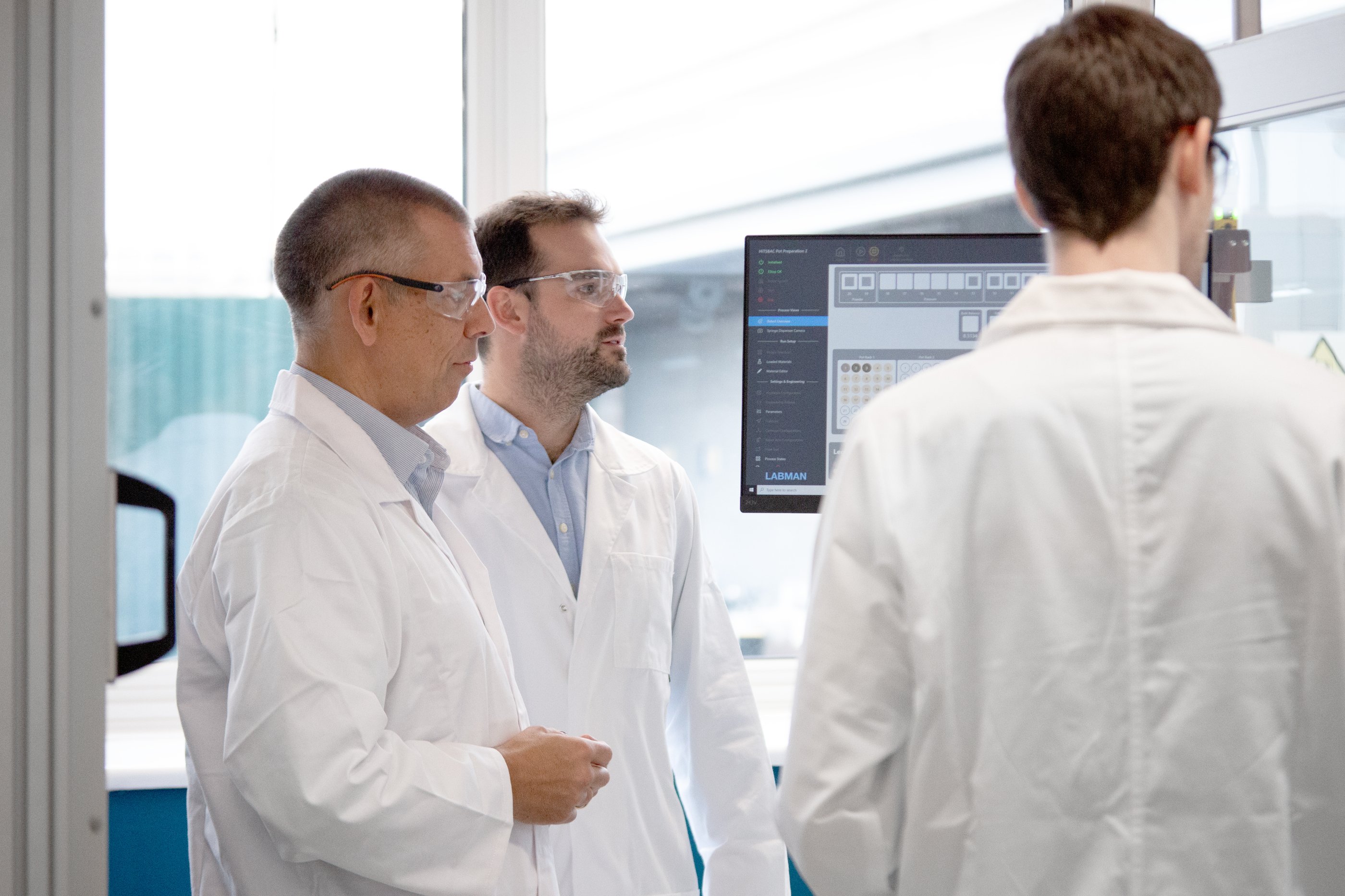Three men in a paint formulation lab