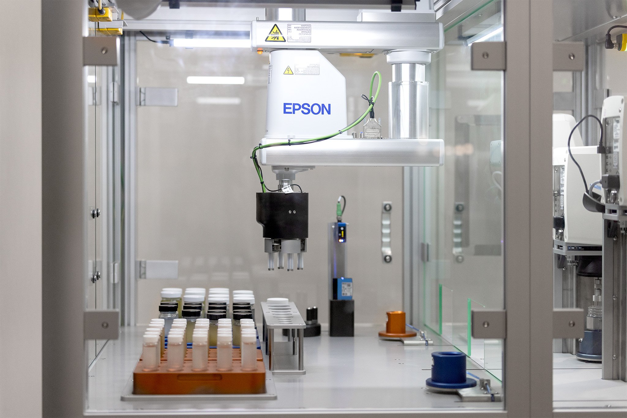 An Epson Scara robot arm integrated into an automated system with glass jars containing liquid