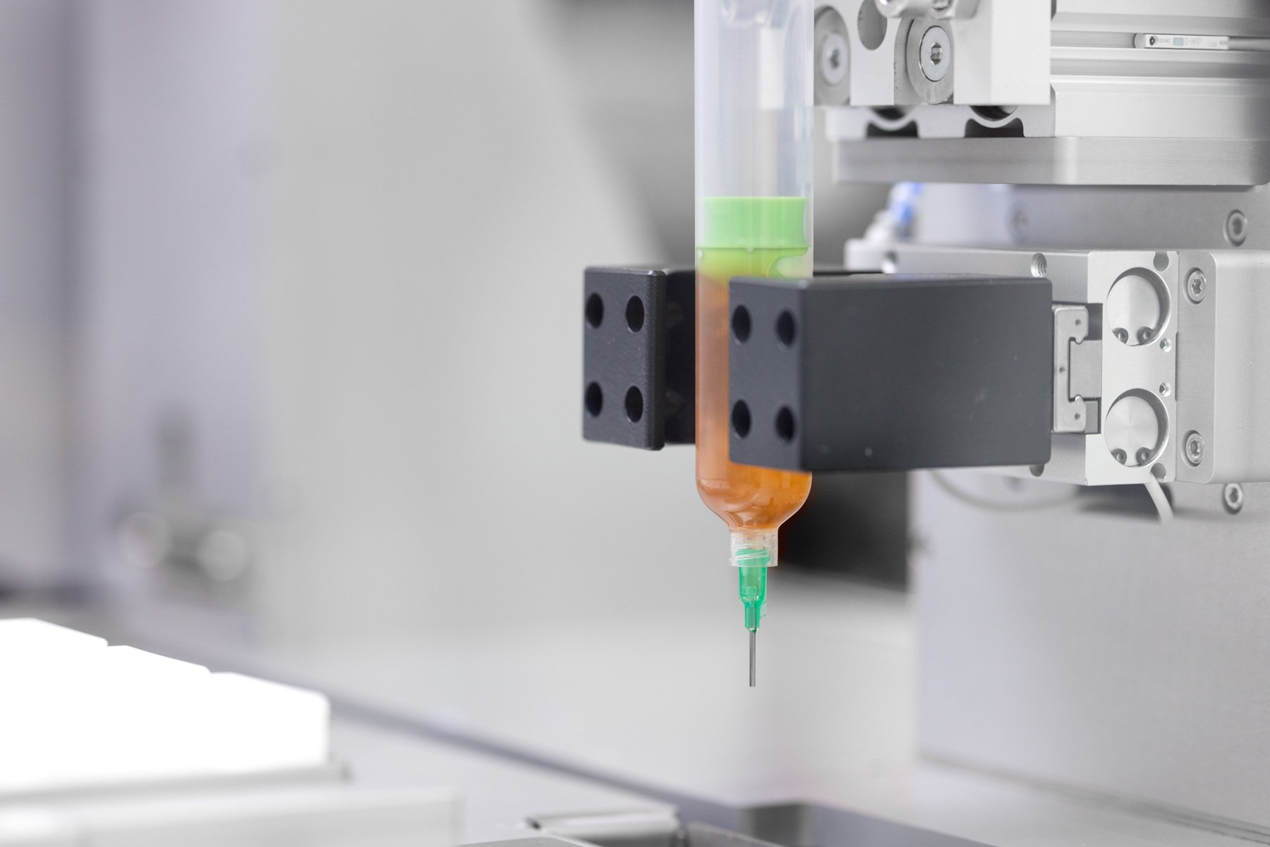 A coloured liquid in a syringe held in an automated gripper