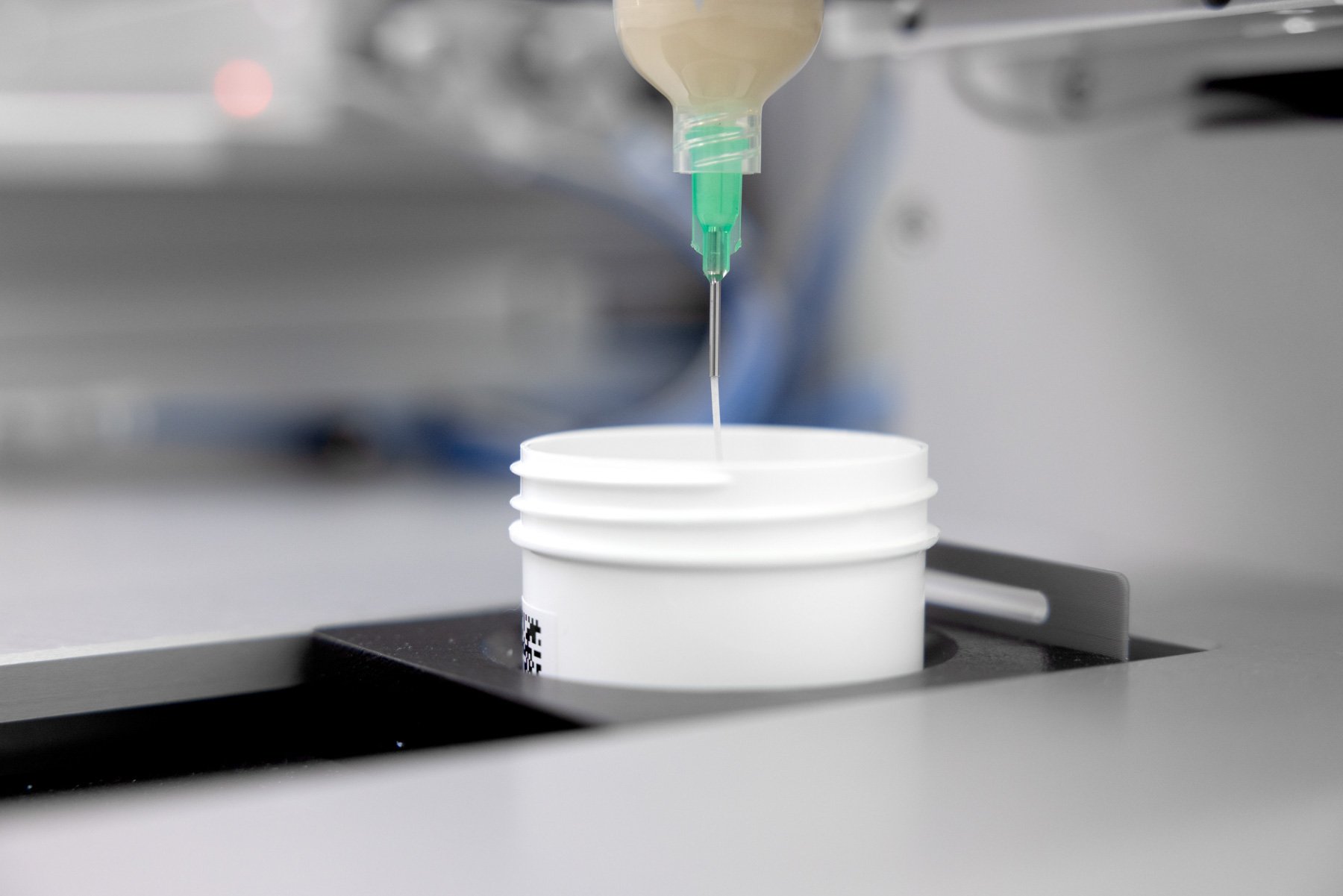 A formulation being dispensed from a syringe into a pot on an automated system