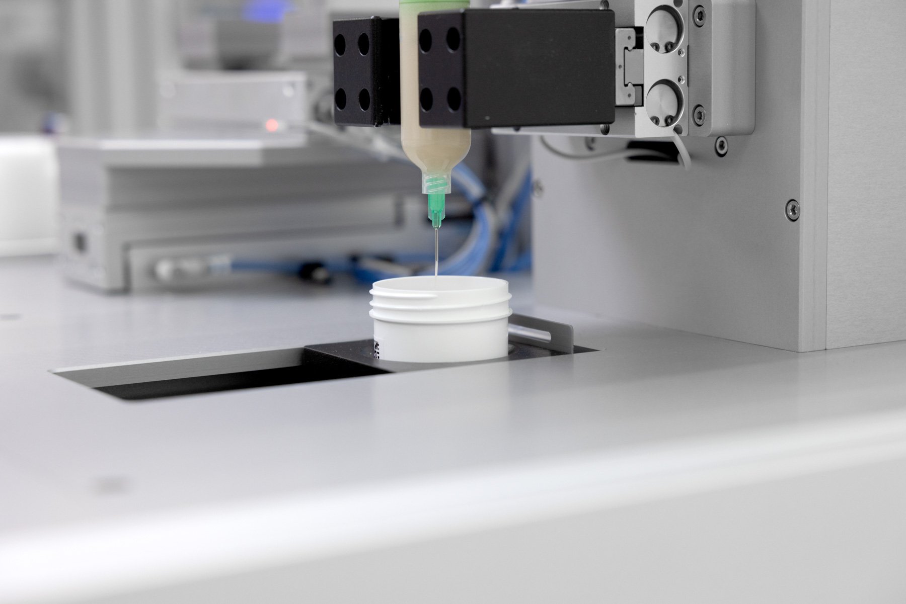 A formulation being dispensed from a syringe into a pot on an automated system