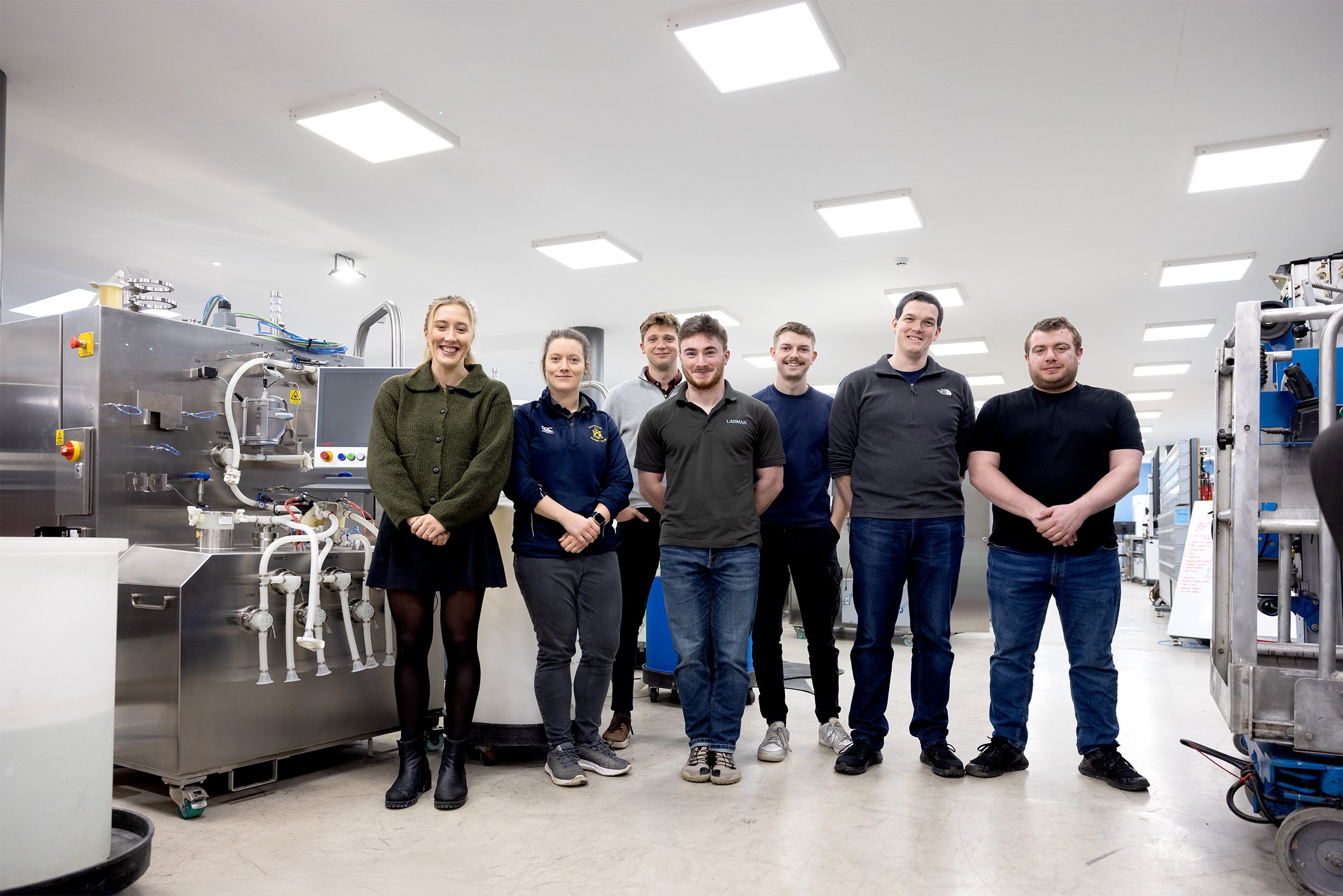 A group of smiling bioprocess engineers in a factory