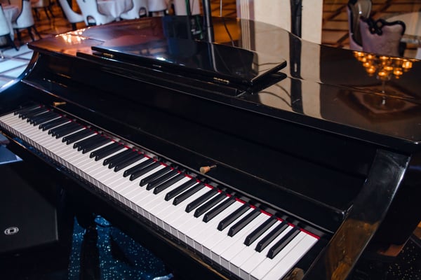 Close-up of a black grand piano in a restaurant setting, highlighting the care offered by OverEasyMovers in Agoura Hills Special Items Handling.