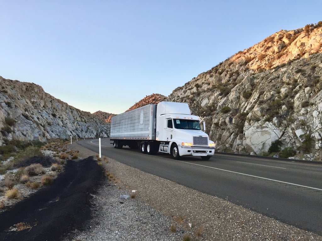 Long-distance moving truck driving through a canyon, representing Anaheim moving company OverEasyMovers.