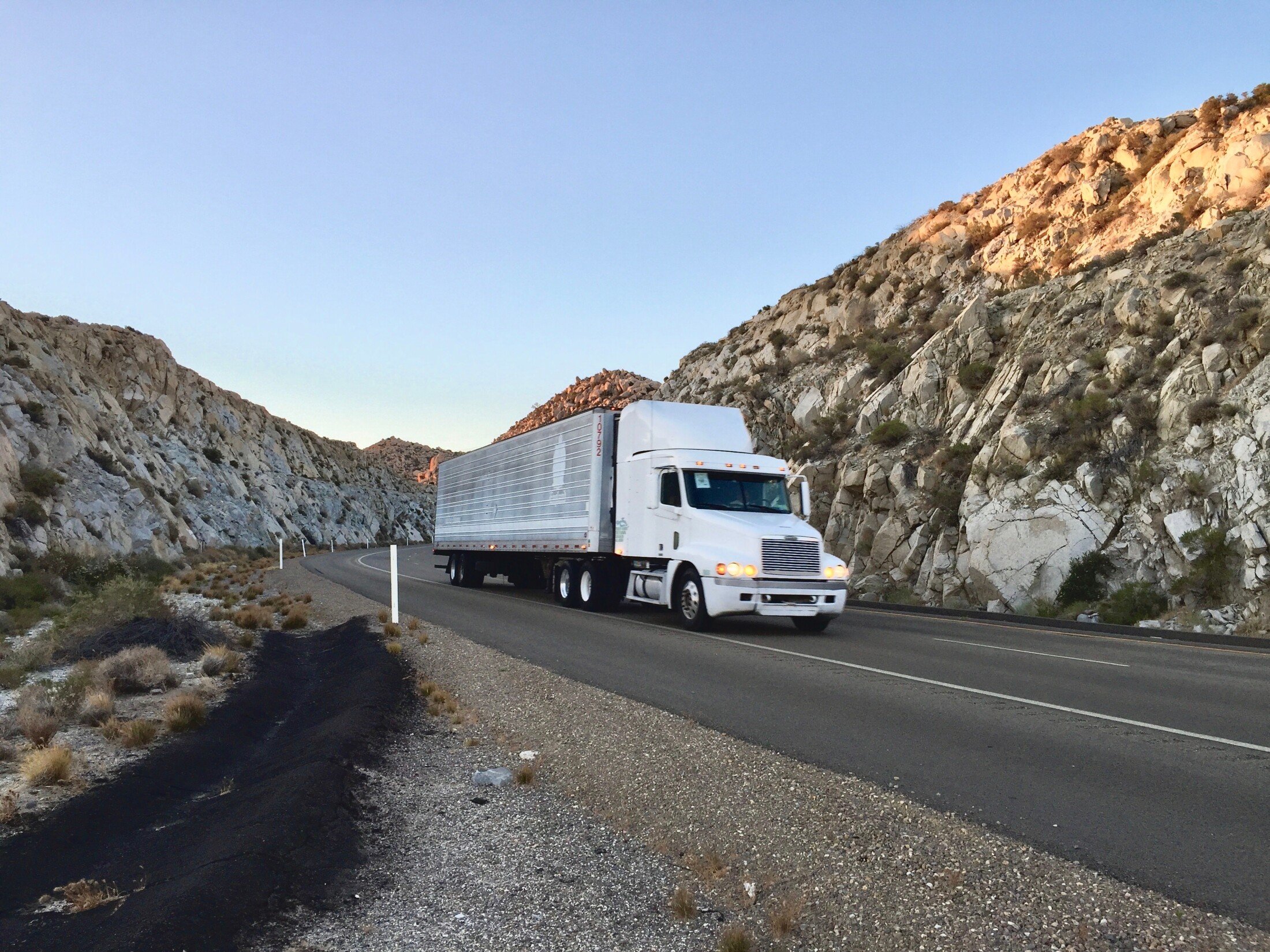Planning Your Long-Distance Moving Anaheim: Expert Tips & Tricks 1 Long-distance moving truck driving through a canyon, representing Anaheim moving company OverEasyMovers.