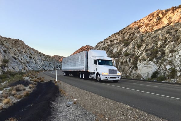 Long-distance moving truck driving through a canyon, representing Anaheim moving company OverEasyMovers.