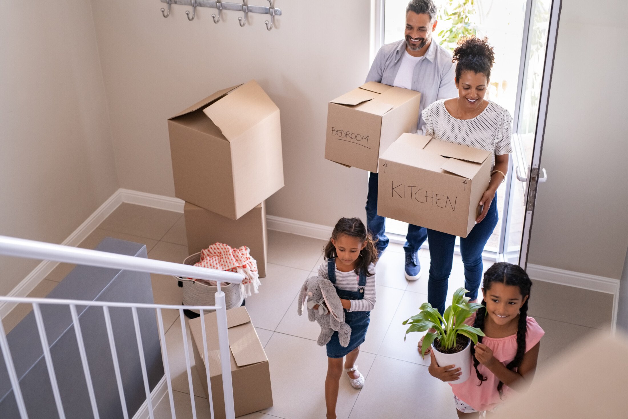 Family carrying moving boxes into a new home with help from OverEasyMovers in Alhambra.