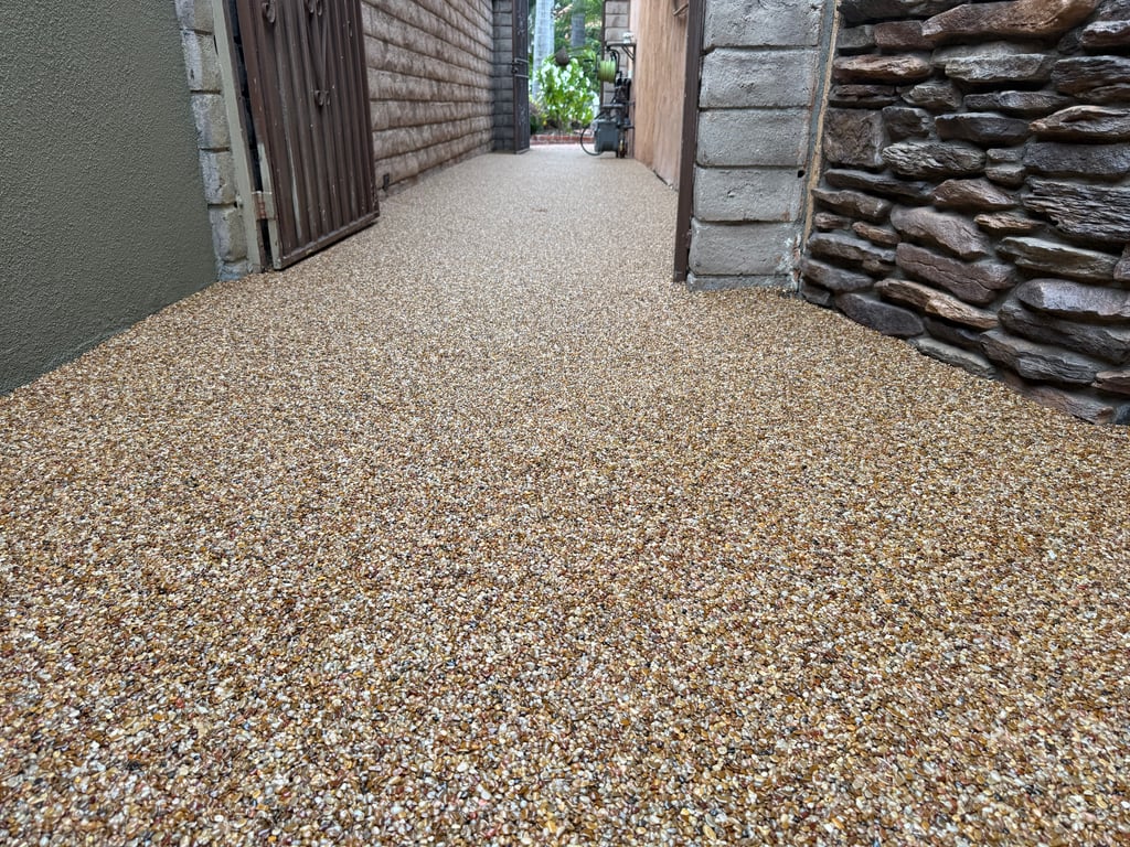 Stone Carpet Walkway – Durable Epoxy Pebble Overlay Stone carpet walkway with natural river pebbles and epoxy binder, creating a seamless, slip-resistant surface between residential walls.