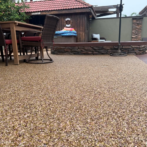 Outdoor patio with pebble epoxy stone carpet flooring by Stone Carpet Pros, featuring natural river pebbles and UV-stable epoxy for a durable, slip-resistant surface.