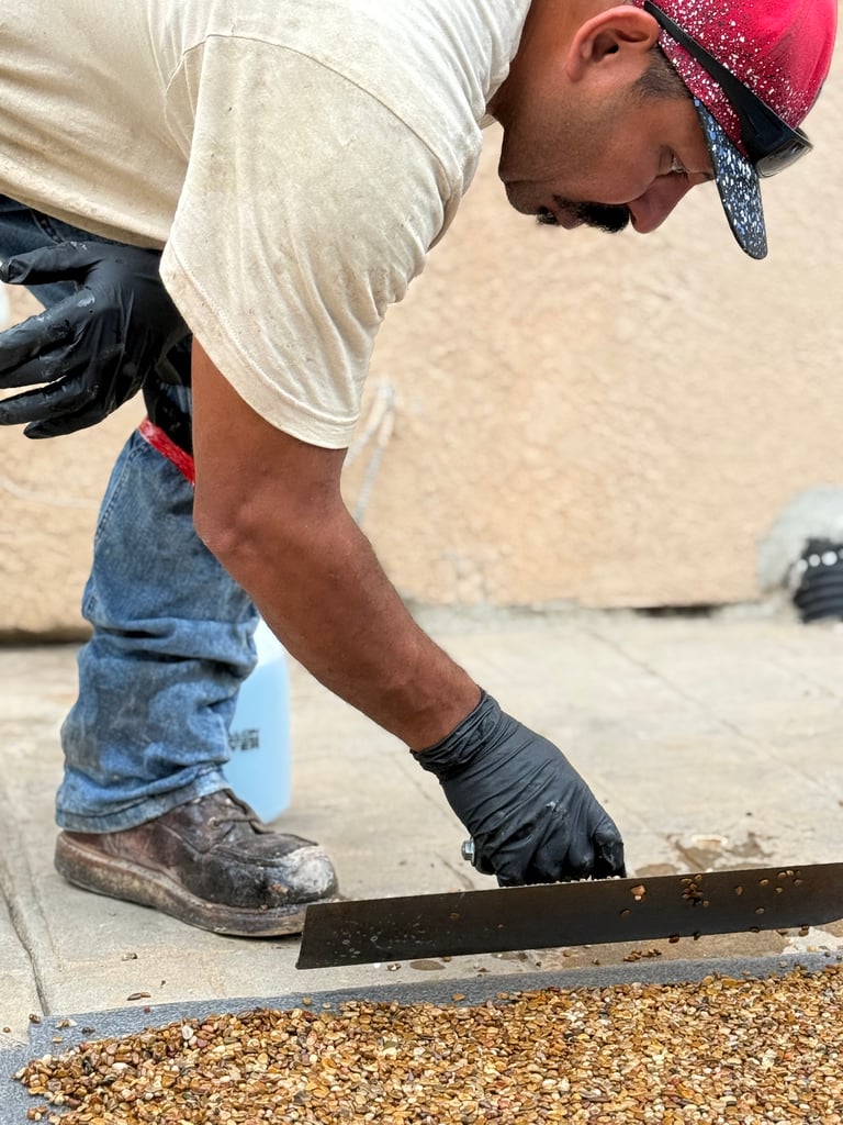 Worker applying natural stone carpet to a cracked concrete pool deck.