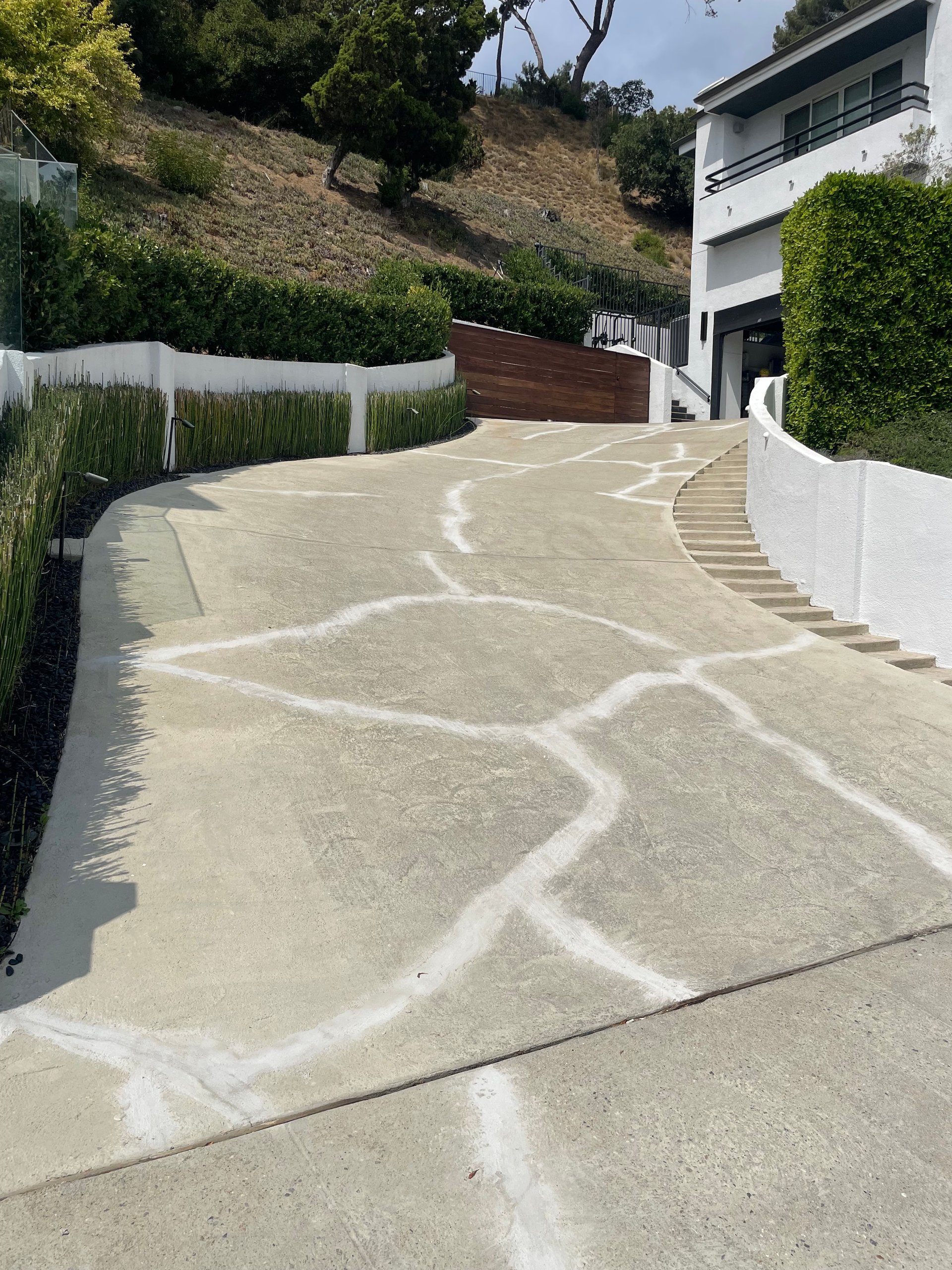 Cracked concrete driveway before resurfacing with pebble epoxy stone carpet.