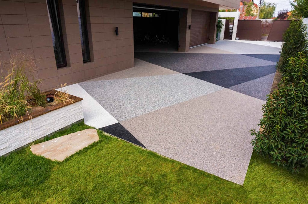 A contemporary home with a stone carpet driveway featuring a striking geometric pattern with different colored aggregates in shades of black, gray, and brown.