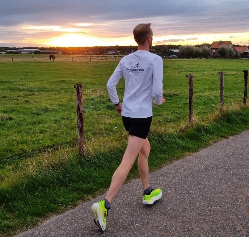 hardloper bij weiland met ondergaande zon