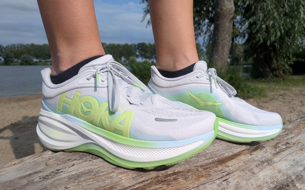 Hardloper toont wit met groene HOKA Clifton PRO tijdens hardlopen in park