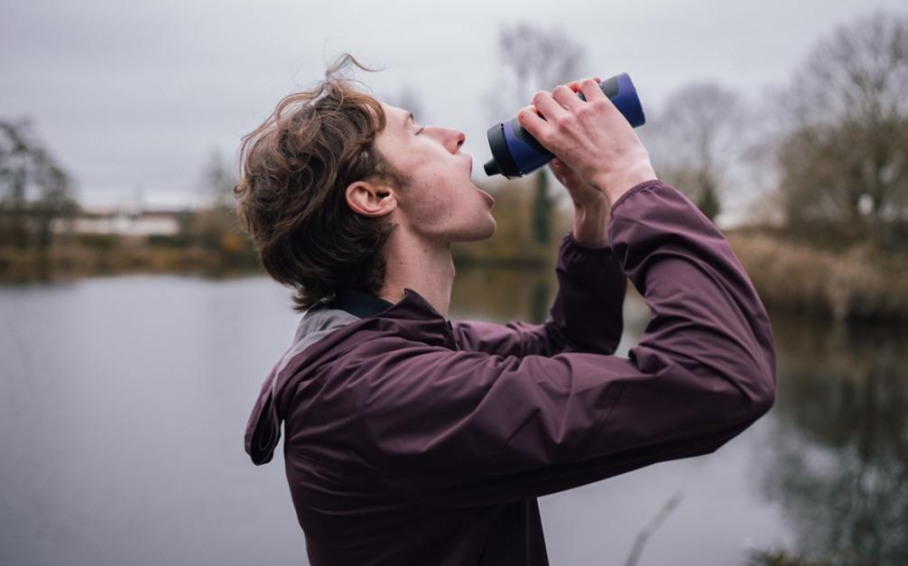 Hardloper drinkt sportdrank als voeding tijdens hardlopen