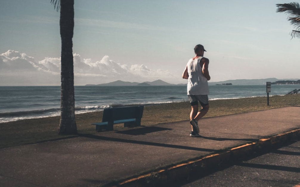 Hardloper loopt hardlooproute op vakantie langs de zee.